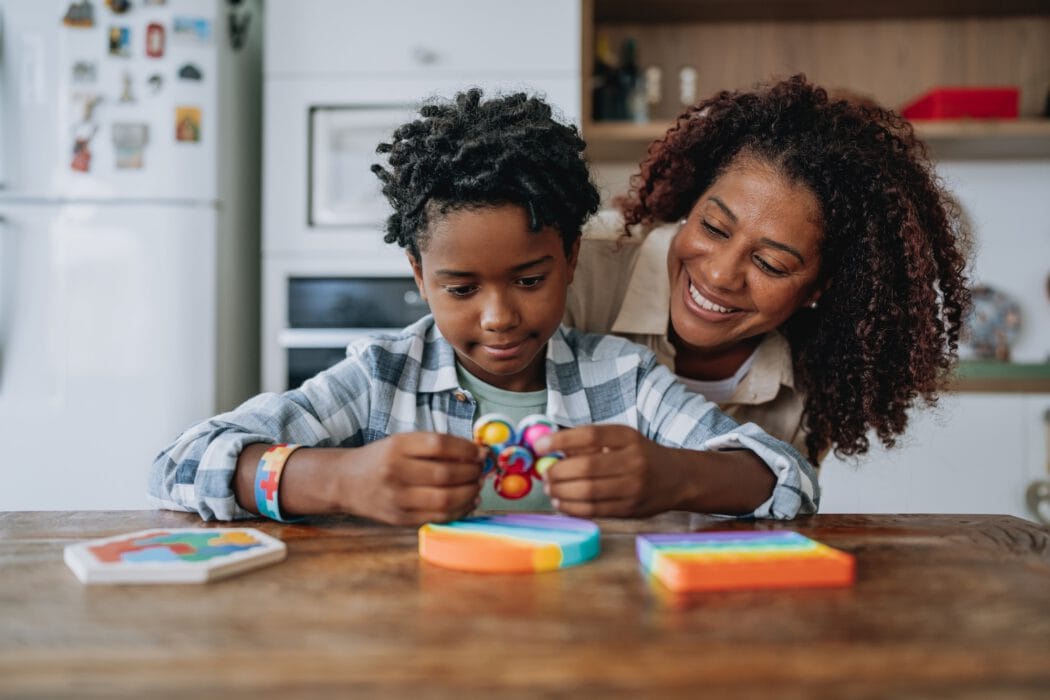 A child plays with a fidget toy as an adult woman offers support for Louisiana citizens with developmental disabilities in a modern kitchen.