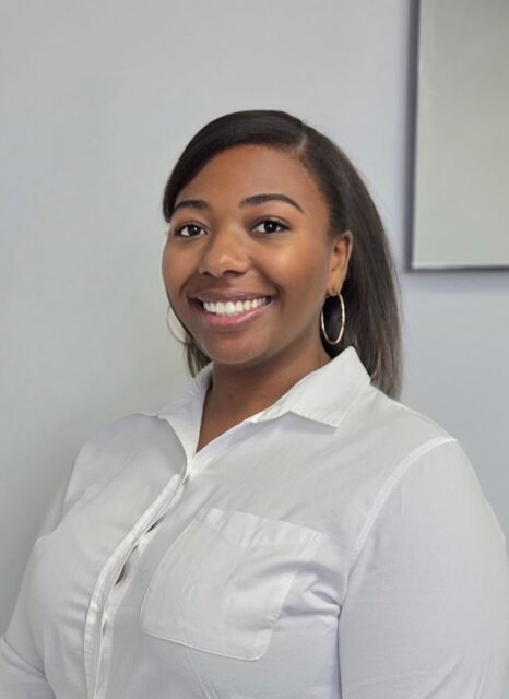 A woman with straight dark hair, wearing hoop earrings and a white shirt, smiles for the Louisiana Developmental Disabilities Council.