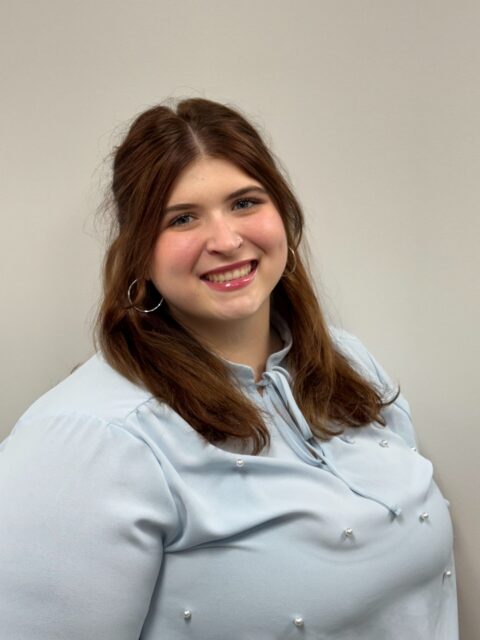 A woman with long brown hair and a light blue blouse smiles, reflecting support for Louisiana citizens with developmental disabilities.